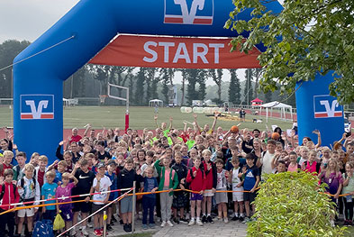 Große Gruppe von Kindern unter dem Marathonbogen der Volksbanken Raiffeisenbanken bei der Veranstaltung Lets play sports